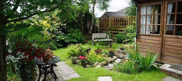 small garden with a summerhouse, seating and pond with slab stepping stones.